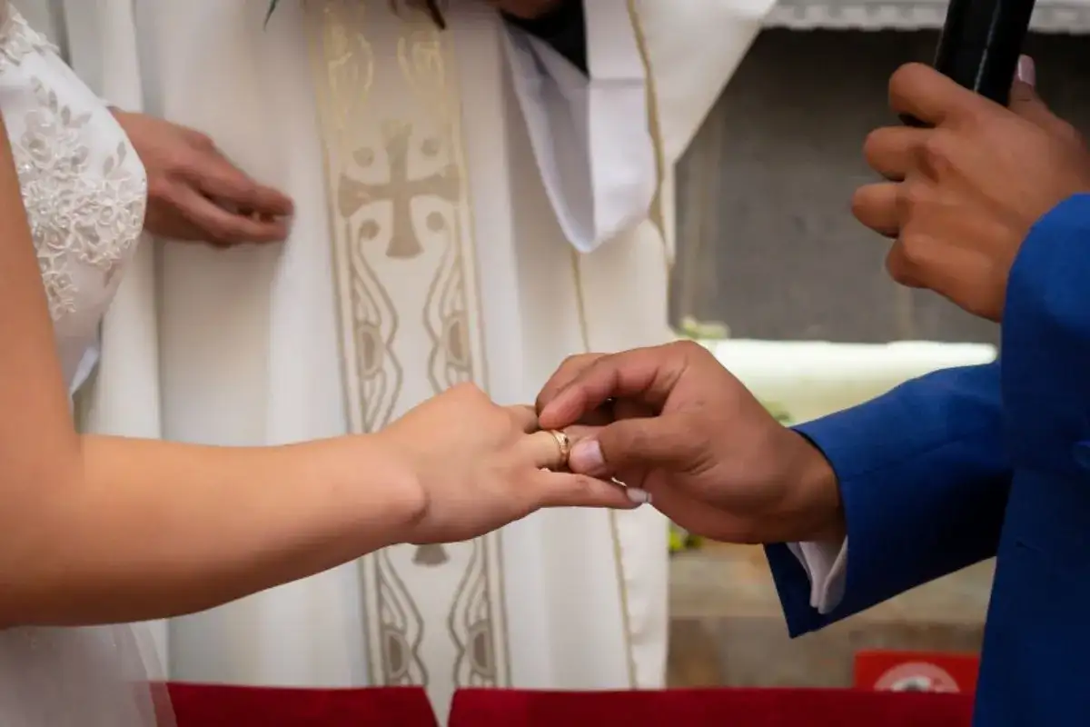 Pan młody zakłada obrączkę na palec panny młodej. Ceremonia ślubna, gdzie co Bóg złączył, niech człowiek nie rozdziela.