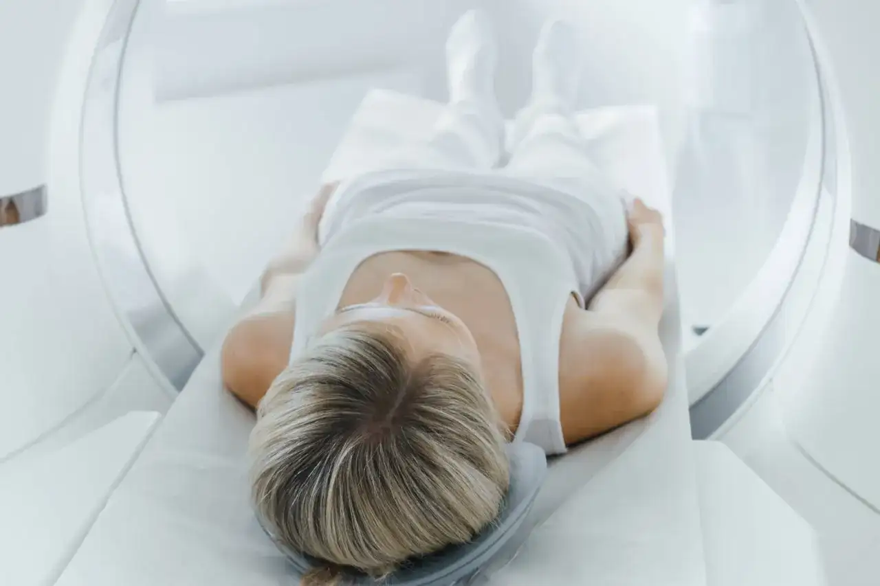 Kobieta leży na stole do rezonansu magnetycznego, przygotowując się do badania tk klatki piersiowej.