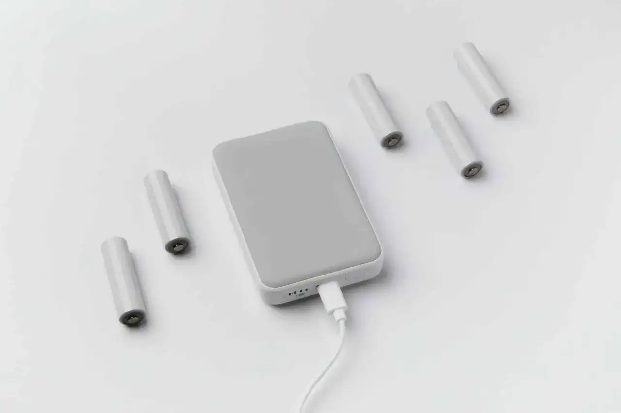 Szare baterie i powerbank podłączony kablem. Czy można mieć powerbank w bagażu podręcznym? Tak, zazwyczaj można.