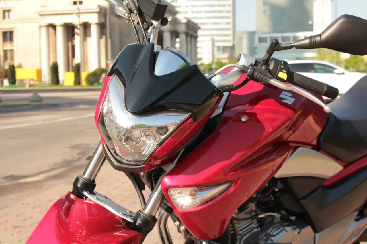 Błyszczący, czerwony motocykl Suzuki Inazuma z czarnym akcentem na przedniej owiewce, gotowy do jazdy po mieście.