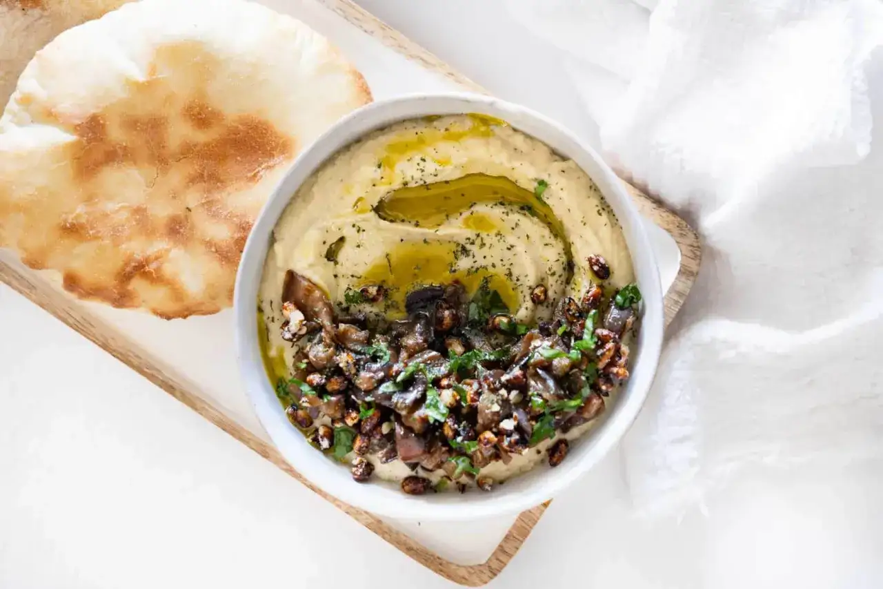 Un bol de caviar d'aubergine libanais, garni d'huile d'olive et de persil, servi avec du pain pita. Une recette savoureuse à découvrir.