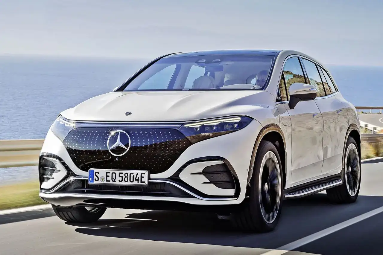 Biały Mercedes EQS SUV jedzie wzdłuż malowniczego wybrzeża.