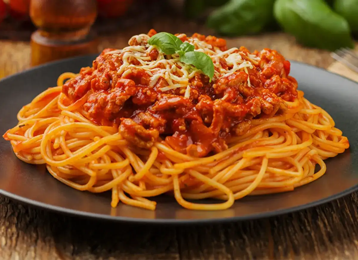 Pyszne spaghetti bolognese z mielonym mięsem, polane sosem pomidorowym i posypane serem. Idealne pytanie: jakie mięso do spaghetti?