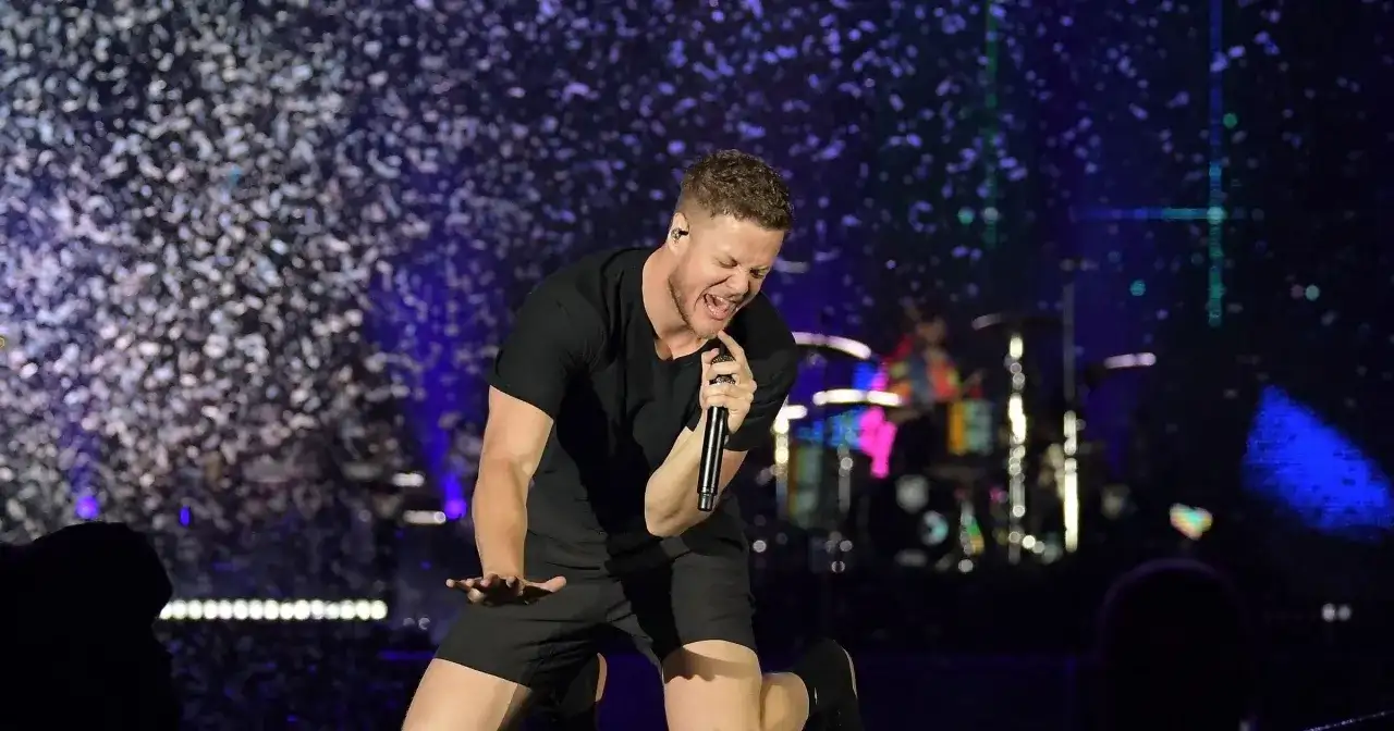 Imagine Dragons wokalista Dan Reynolds śpiewa z pasją na scenie, otoczony konfetti.
