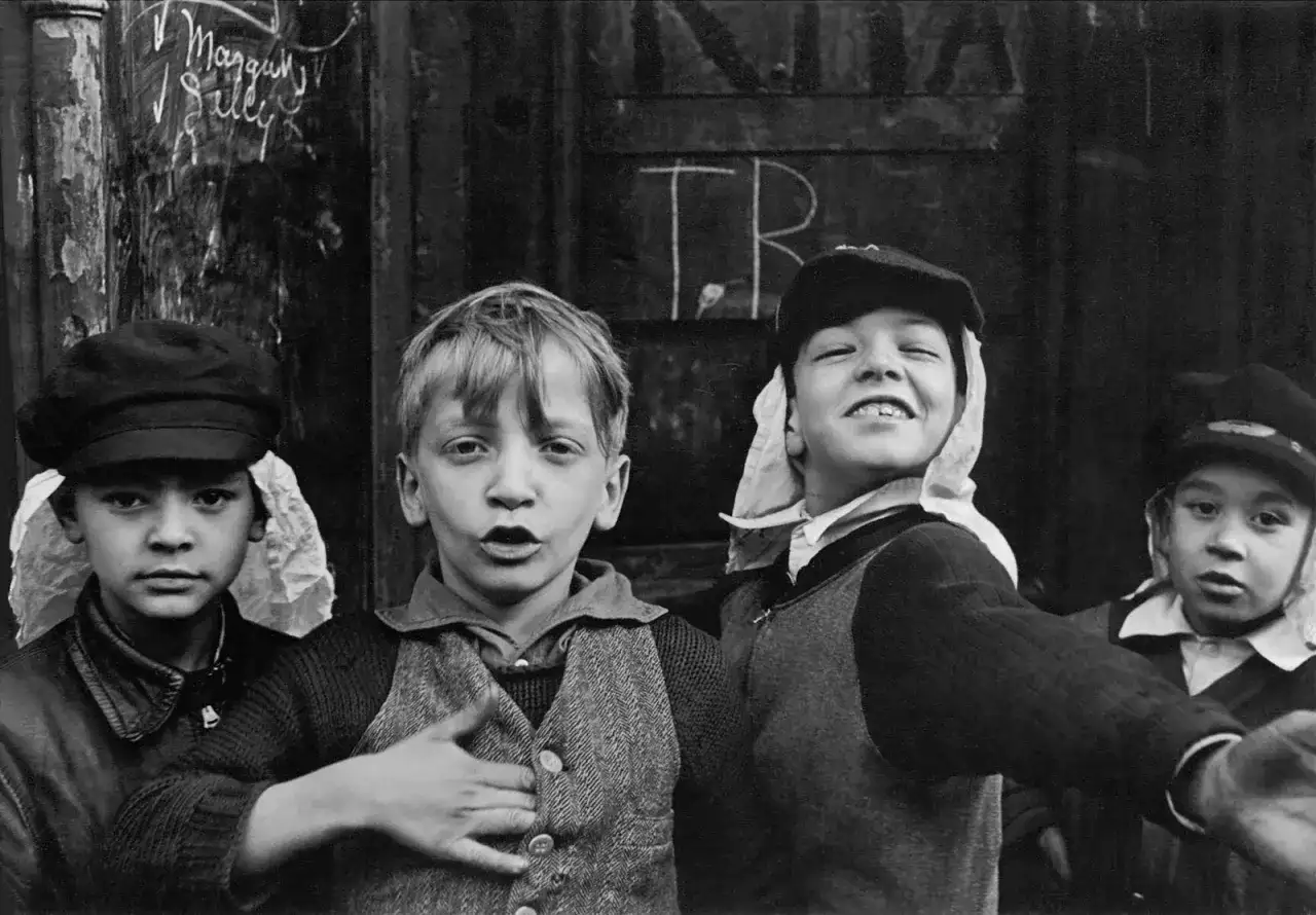 Bambini con cappelli, un'immagine che ricorda i grandi fotografi famosi, con un'espressione vivace e un gesto di invito.