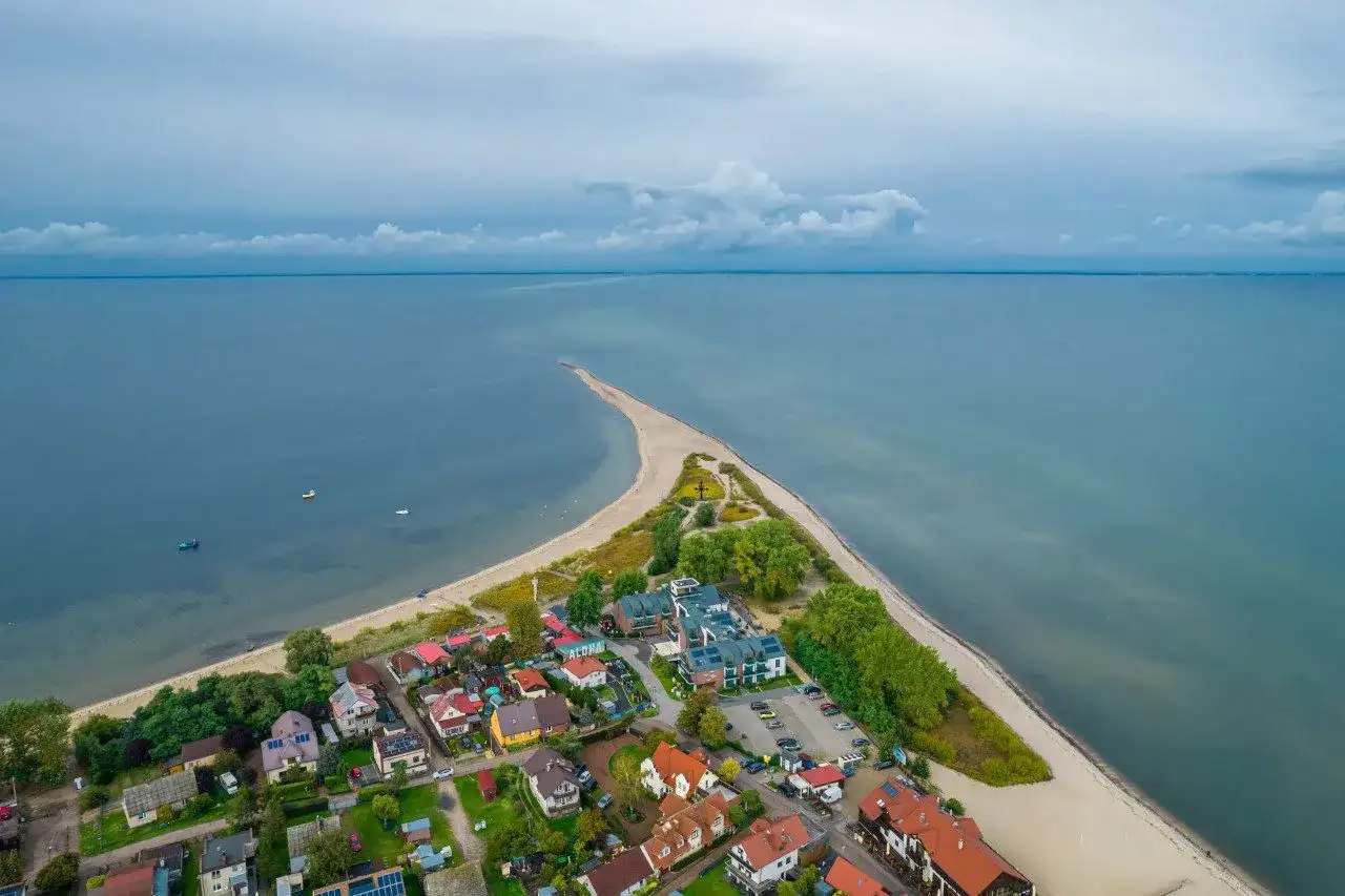 Malownicza miejscowość na wybrzeżu bałtyckim, z domkami i hotelem, otoczona plażą i morzem.