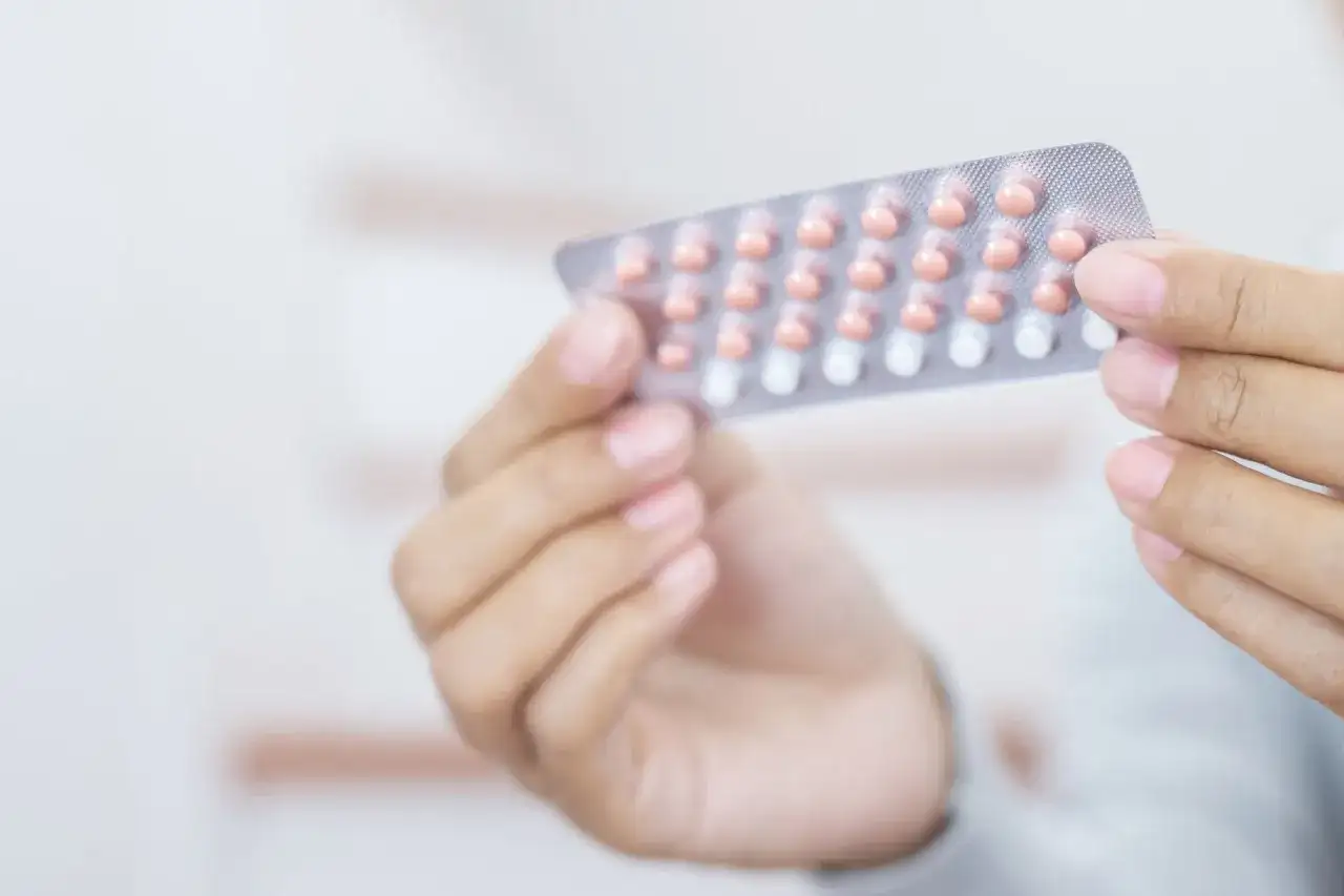 Dłoń trzyma blister z tabletkami antykoncepcyjnymi. Wiele osób szuka informacji o tabletki antykoncepcyjne nazwy.