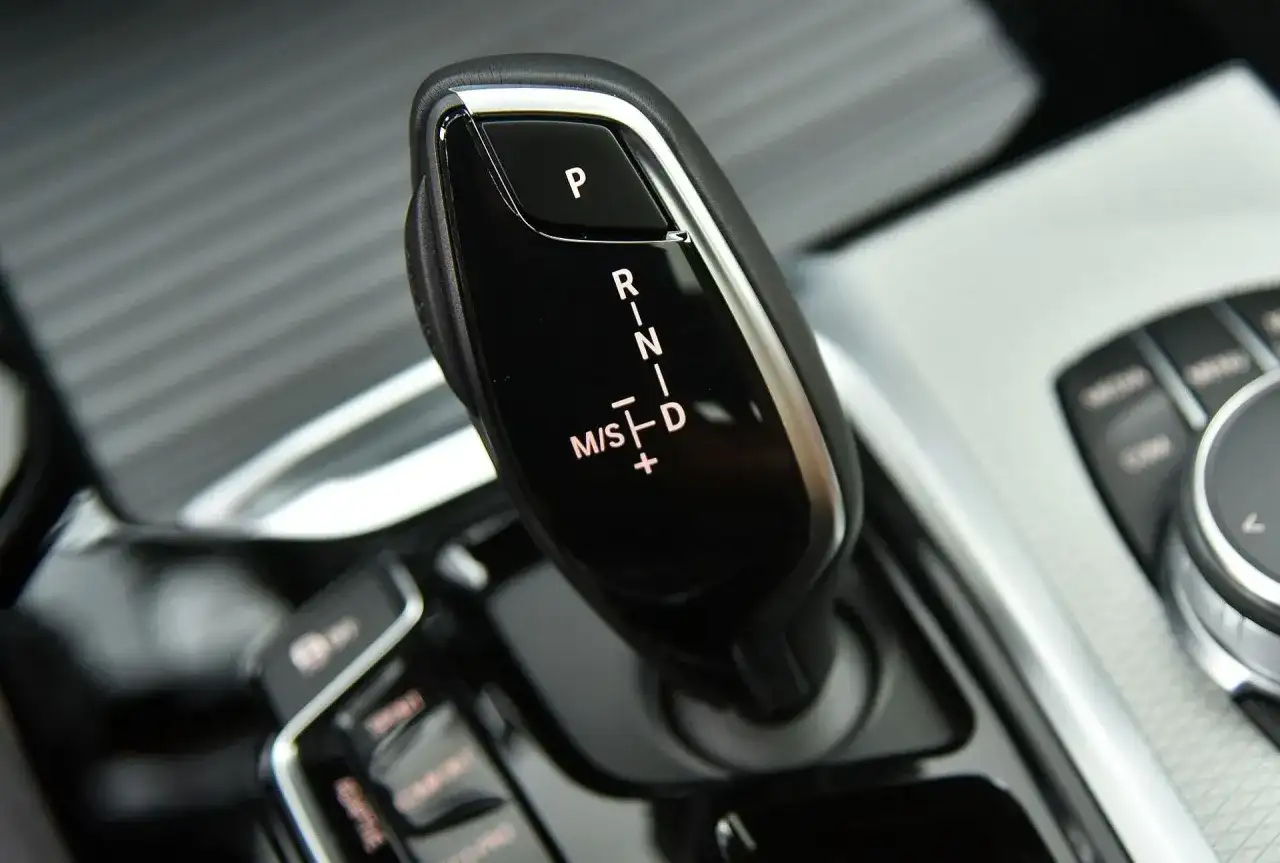 Dźwignia zmiany biegów w BMW G01. Widoczne oznaczenia P, R, N, D oraz M/S z możliwością ręcznej zmiany biegów.