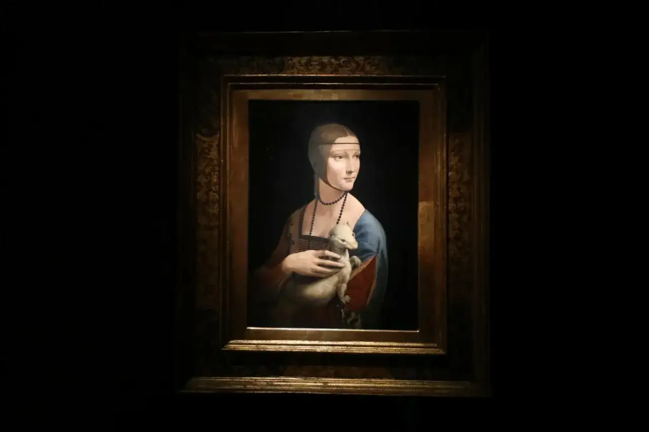 Obraz Dama z łasiczką, Leonarda da Vinci. Młoda kobieta w niebieskiej sukni trzyma w ramionach białego zwierzątko.