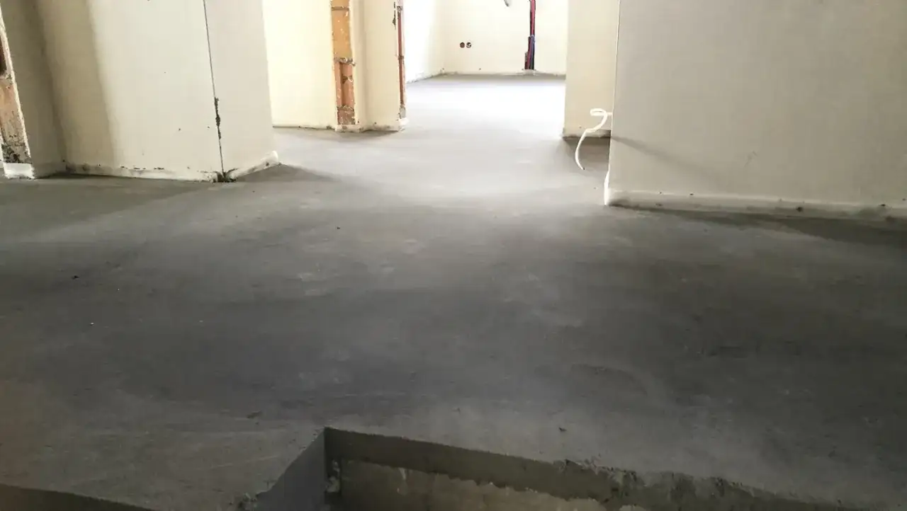 Surowy, betonowy jastrych co to? To podłoga gotowa na wykończenie. Widać fragmenty ścian i instalacji.