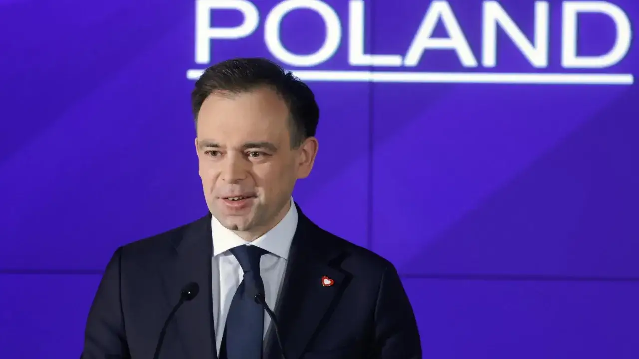 Mężczyzna w garniturze przemawia na tle napisu "POLAND". Dyskutuje o przyszłości cyfrowej gospodarki i potencjalnym podatku cyfrowym.