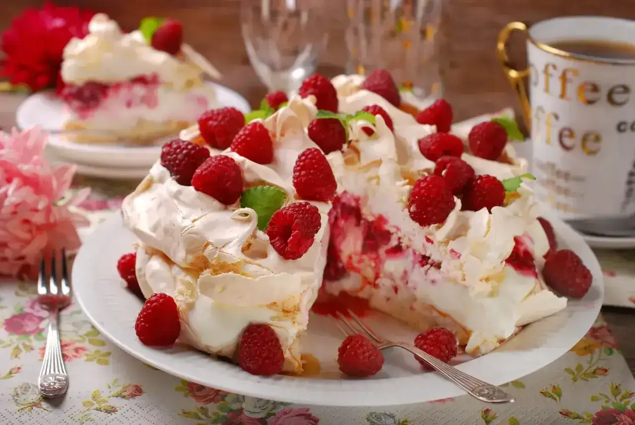Pyszny tort bezowy z mascarpone i bitą śmietaną, ozdobiony malinami. Idealny na deser!