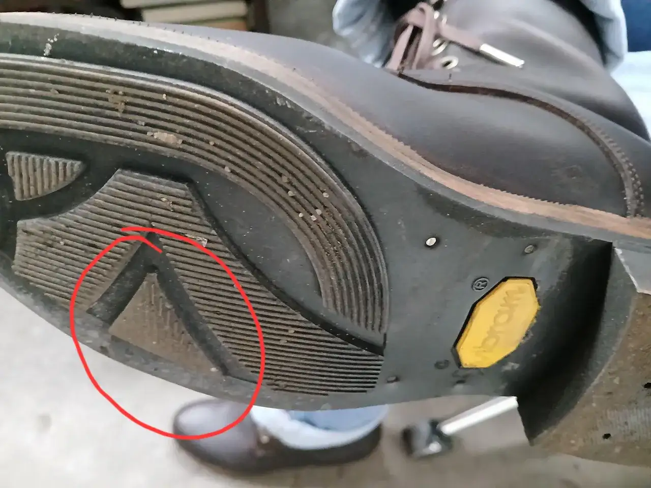 Zużyta podeszwa Vibram w bucie górskim. Czerwone koło wskazuje na uszkodzenie, które może być jedną z przyczyn szybkiego zużycia podeszwy Vibram.