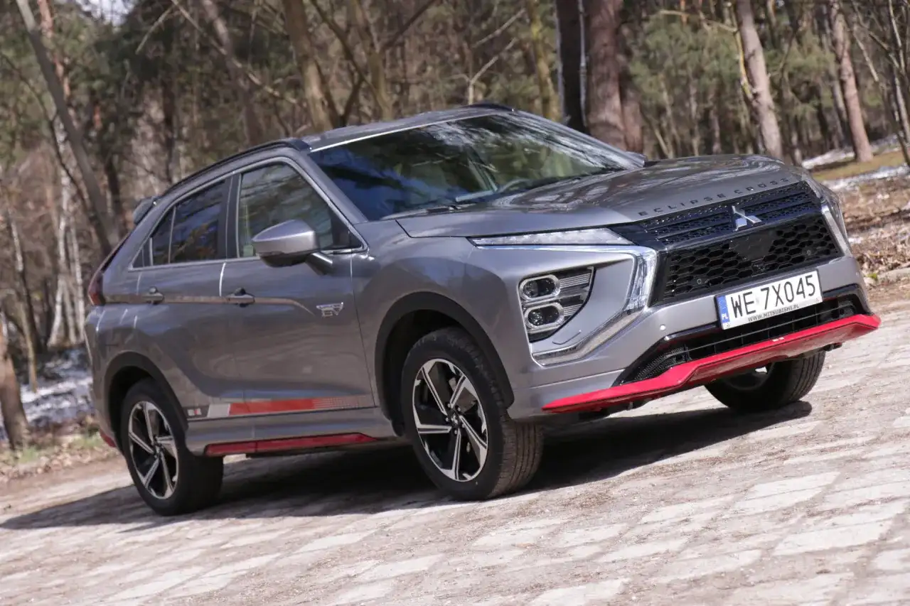 Szary Mitsubishi Eclipse Cross EV na leśnej drodze. Wiele pozytywnych mitsubishi eclipse cross opinie potwierdza jego wszechstronność.