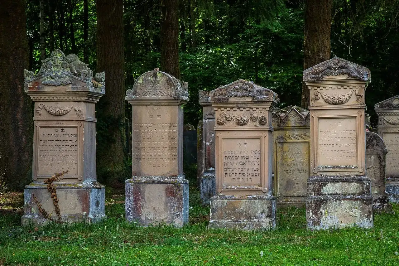 Nagrobki z inskrypcjami hebrajskimi, niektóre z widocznymi pęknięciami, sugerującymi wady materiałowe płyt granitowych.