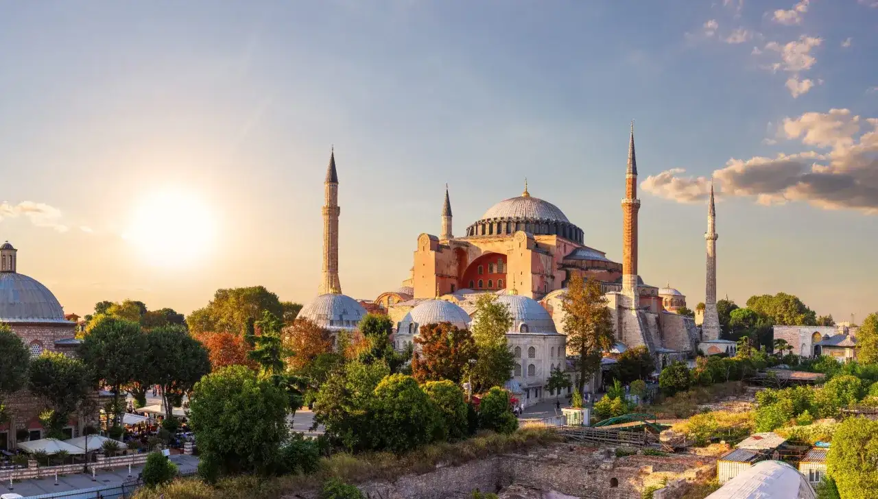 Majestatyczny meczet Hagia Sophia w Stambule, z minaretami i kopułami, oświetlony zachodzącym słońcem.