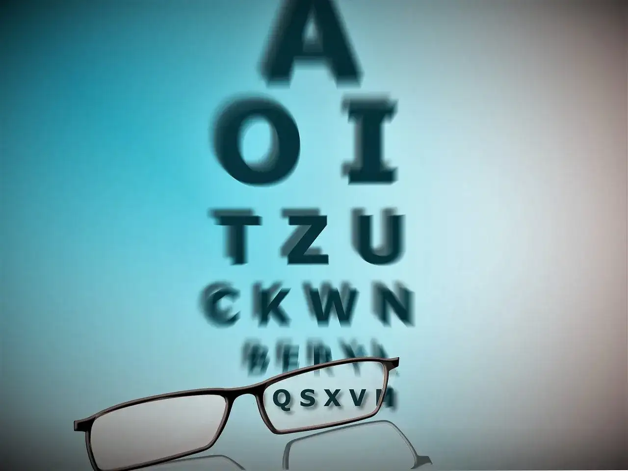 Okulary na tle tablicy Snellena, litery rozmazane, symbolizujące pogorszenie wzroku.