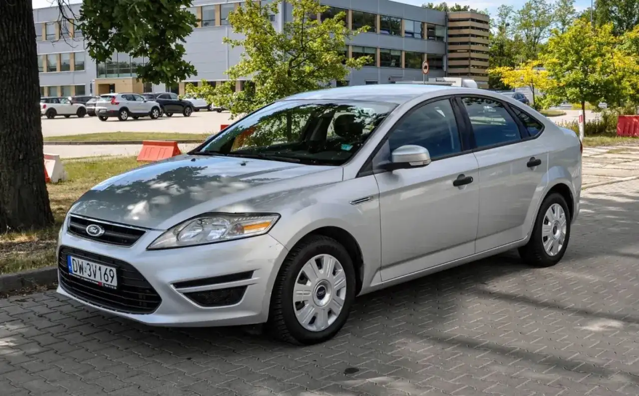 Srebrny Ford Mondeo MK4 2.0 TDCI zaparkowany na kostce brukowej przed budynkiem.