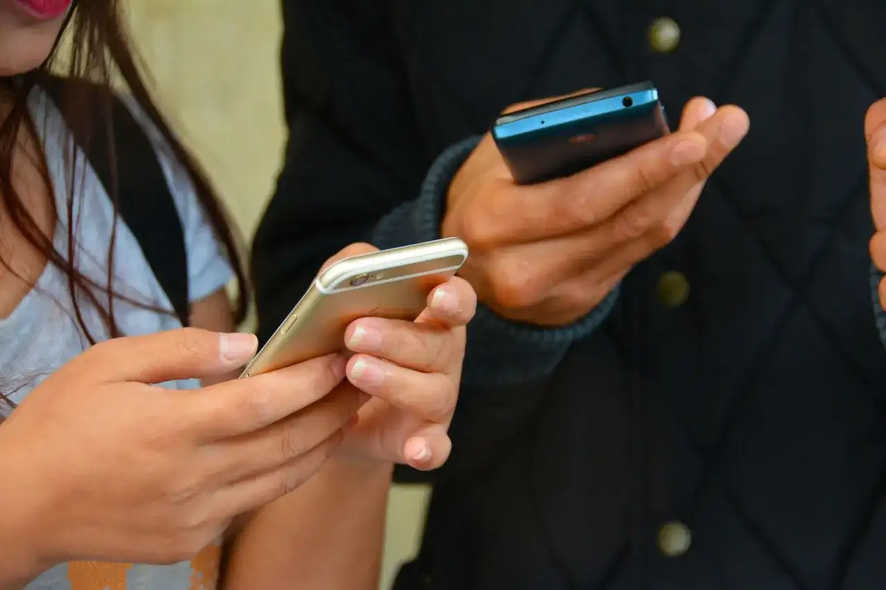 Dwie osoby trzymają telefony. Zastanawiasz się, jak sprawdzić, gdzie ostatnio logował się telefon?