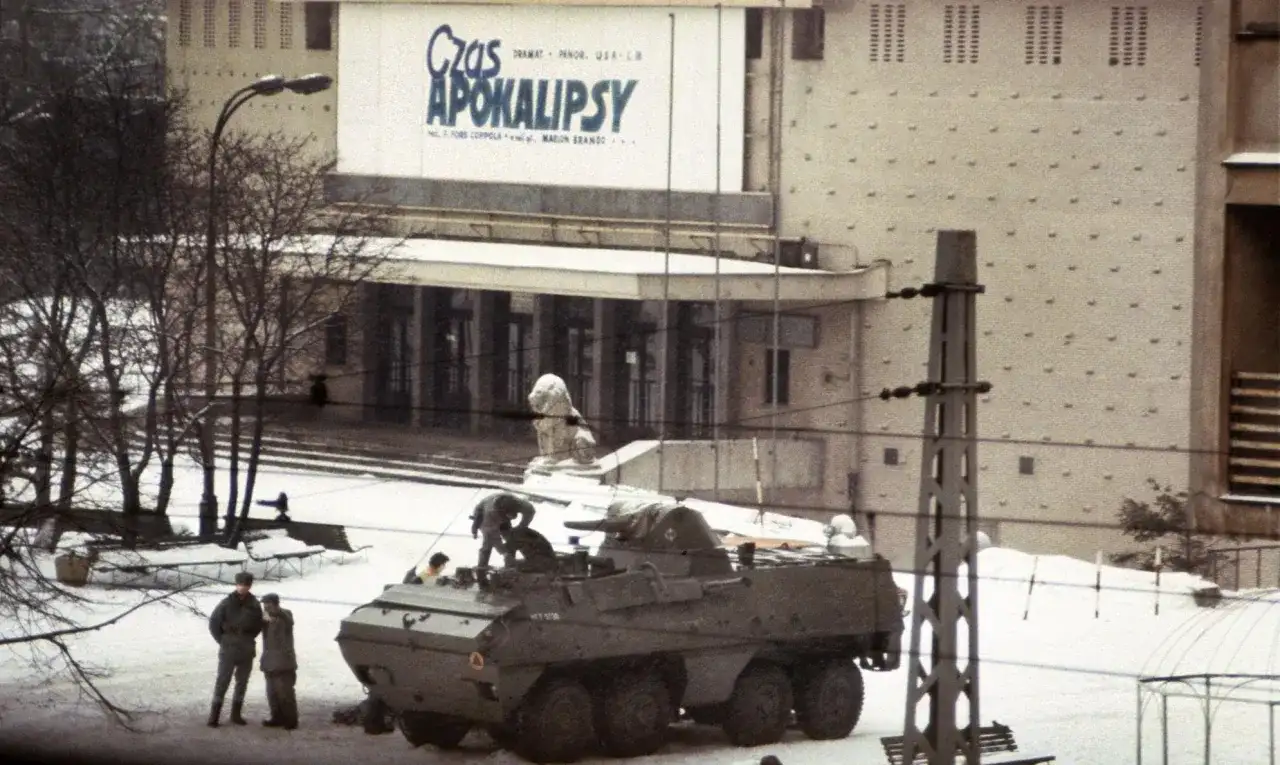 Wóz bojowy na śniegu, ludzie w mundurach, budynek z napisem "Czas Apokalipsy". Atmosfera przypomina stan wojenny.