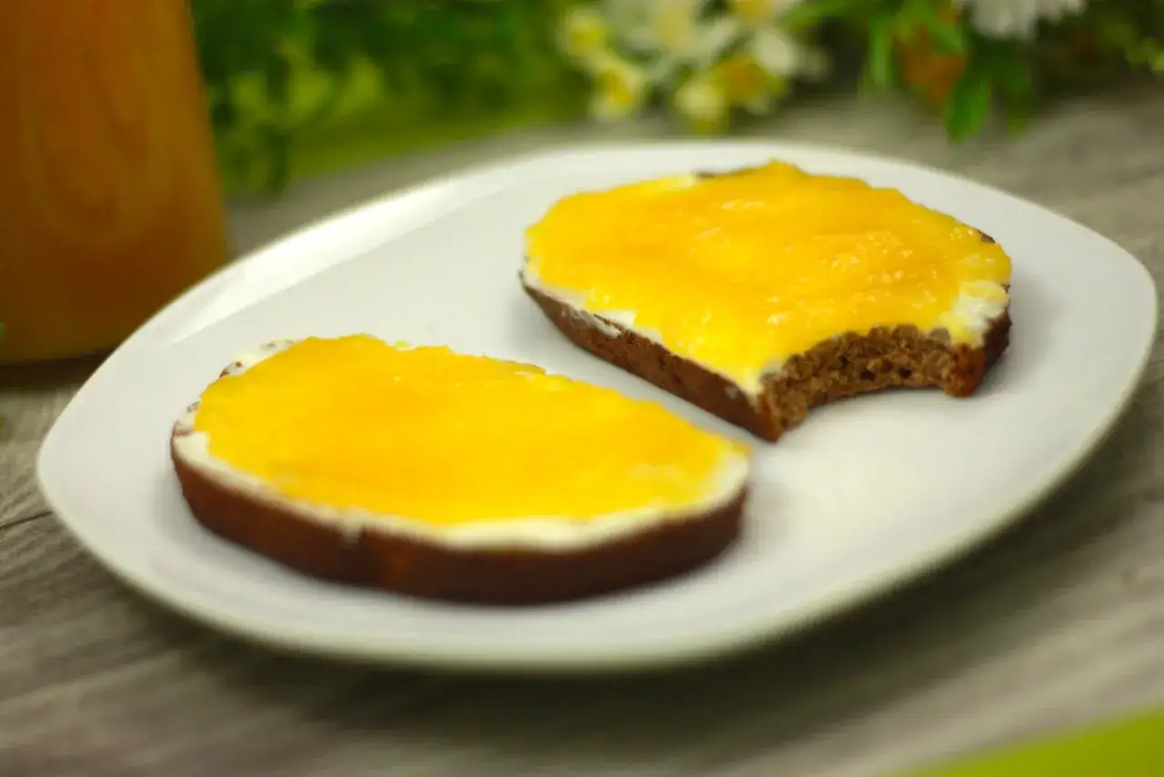 Zwei Scheiben Brot mit Frischkäse und leuchtend gelber, selbstgemachter low carb Marmelade.