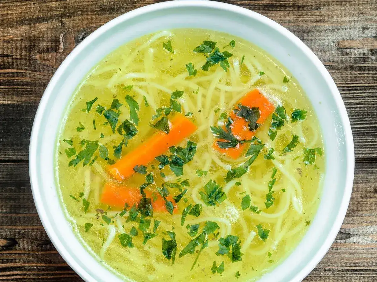Aromaticzny rosół z makaronem, marchewką i natką pietruszki. Czy rosół ma białko? Tak, dzięki mięsu, z którego jest gotowany, dostarcza cennego białka.