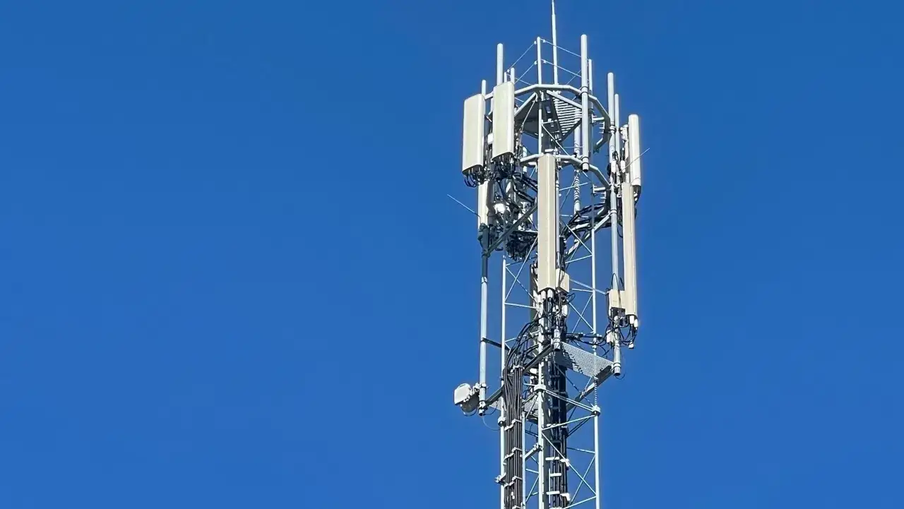Wieża telekomunikacyjna z antenami LTE na tle błękitnego nieba.