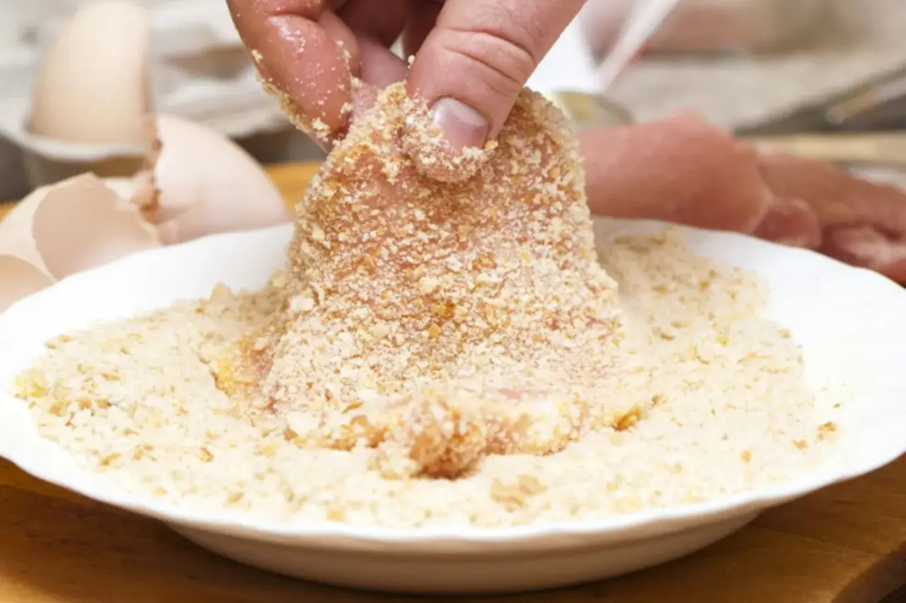 Fleisch wird in eine Schüssel mit **low carb panade** getaucht. Eierschalen liegen daneben.