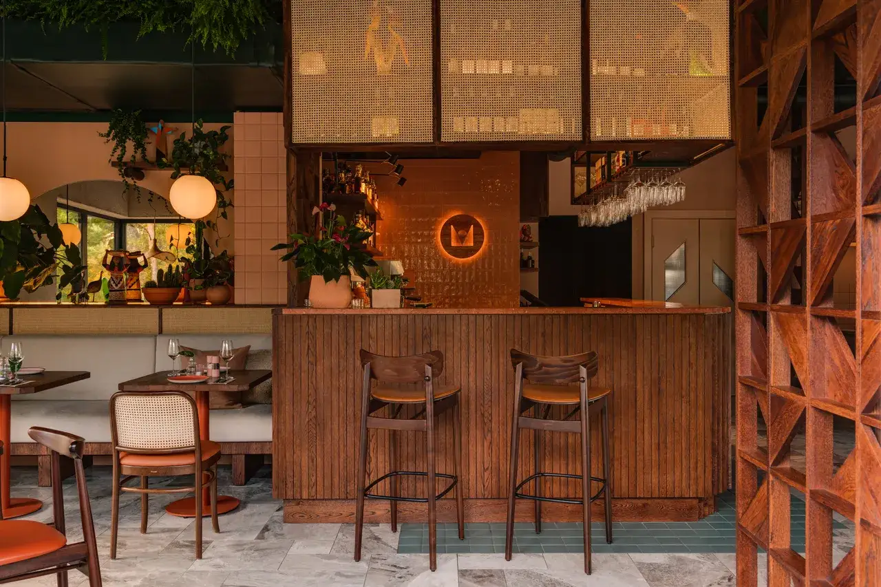 Drewniany bar z krzesłami barowymi i roślinami w przytulnej restauracji.
