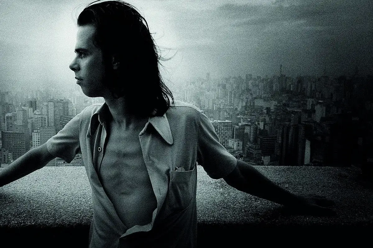 Młody Nick Cave, z rozwianymi włosami, spogląda na miasto. Jego muzyka, jak ten widok, pełna jest mroku i piękna.