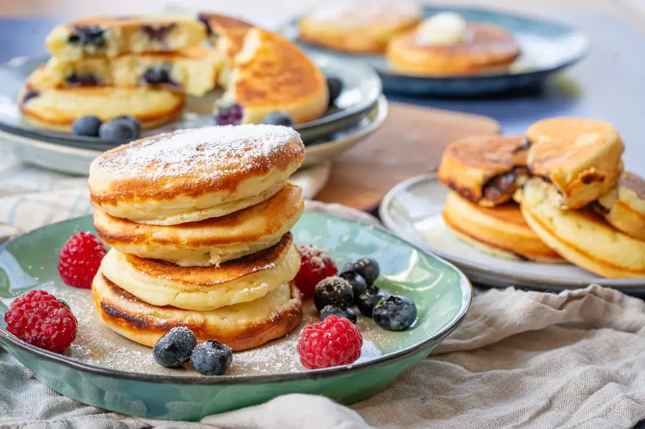 Fluffige Buttermilch Pancakes, bestäubt mit Puderzucker und garniert mit frischen Beeren. Ein Genuss für jeden Morgen!