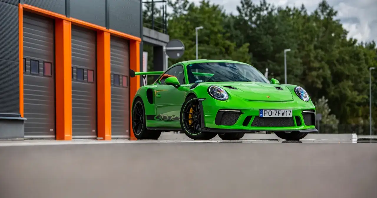 Jaskrawozielony Porsche 911 GT3 RS z czarnym spojlerem i felgami, gotowy do wyjazdu z garażu.