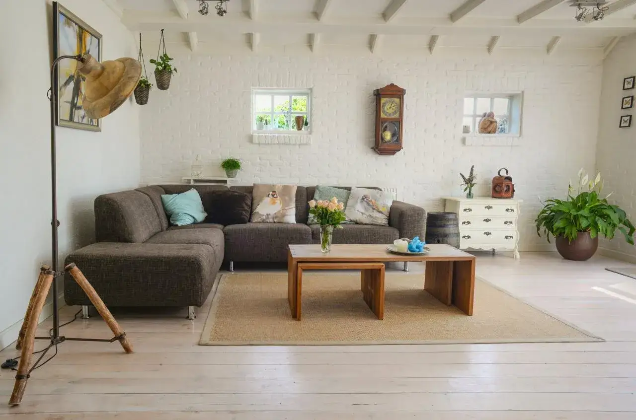 Przytulny salon z ceglaną ścianą, kanapą i stolikiem. Zwróć uwagę na detale, by wiedzieć, na co zwrócić uwagę przy kupnie mieszkania.