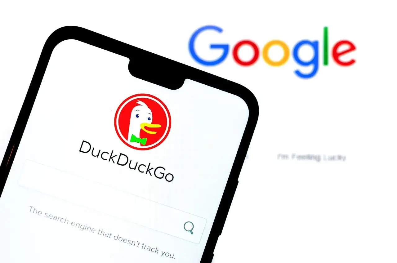 Telefon z DuckDuckGo, jedną z wyszukiwarek internetowych, obok rozmazanego logo Google.