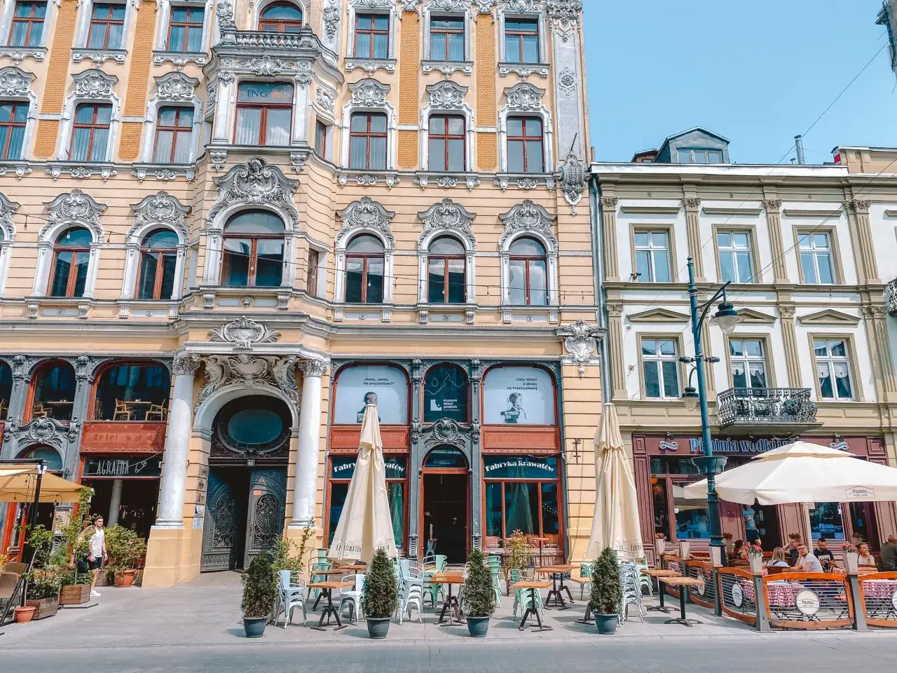 Elegancka kamienica z ogródkiem piwnym i stolikami na chodniku w Łodzi.