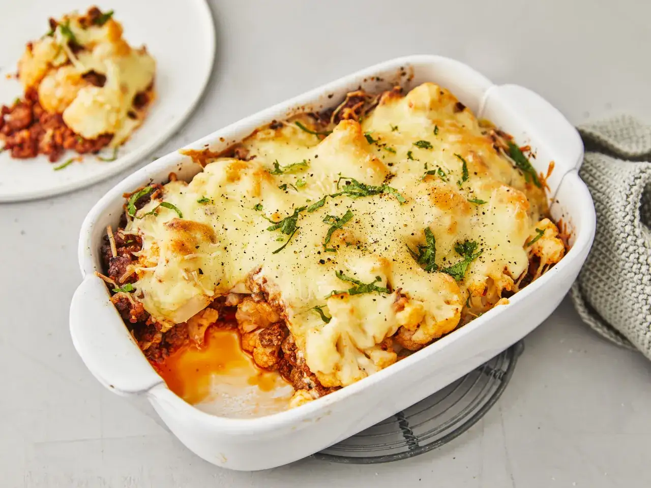 Herzhafter Blumenkohlauflauf mit Hackfleisch, überbacken mit geschmolzenem Käse und garniert mit frischen Kräutern. Ein köstliches Gericht, das Lust auf mehr macht.