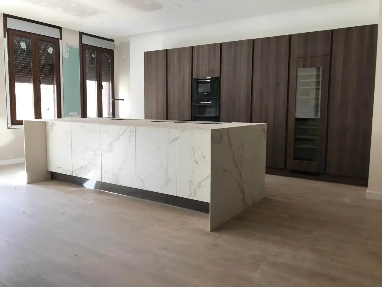 Cocinas modernas con barra central de mármol y gabinetes oscuros.