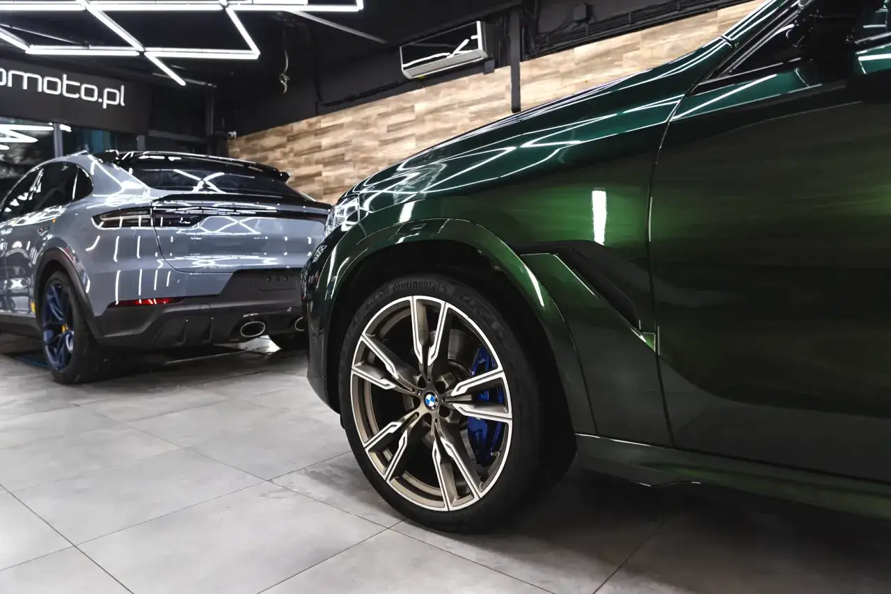 Błyszczące, zielone BMW i szare Porsche w studio auto detailing. Perfekcyjne wykończenie lakieru.