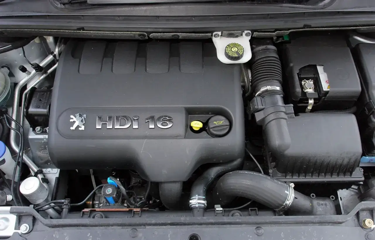Silnik Peugeot 307 2.0 HDI 16V. Widoczny czarny plastikowy kolektor, przewody i akumulator.