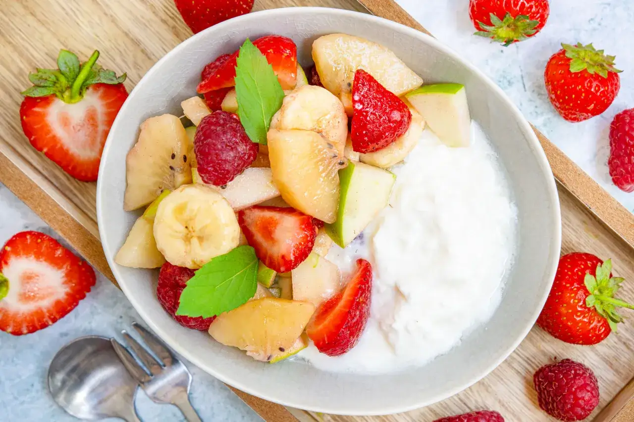 Frischer Obstsalat mit Joghurt, Erdbeeren, Bananen, Äpfeln und Himbeeren. Ein einfaches obstsalat rezept für jeden Tag.