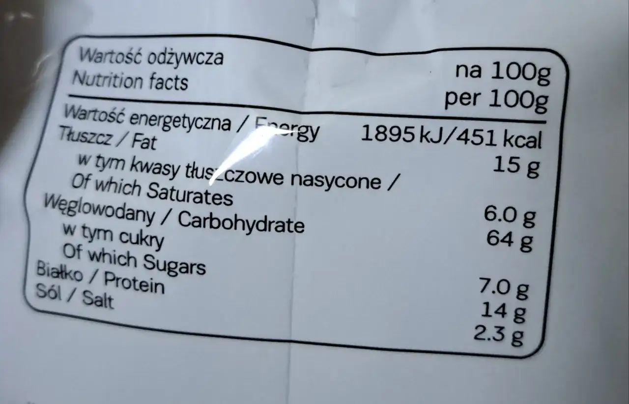 Etykieta z wartościami odżywczymi: 451 kcal na 100g. Tłuszcz 15g, węglowodany 64g, białko 7g. Idealne na 7days kcal.