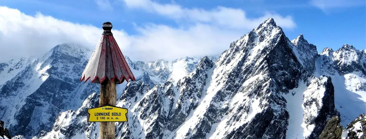 Słowacja góry: szczyt Łomnickie Sedlo (2190 m n.p.m.) w Tatrach Wysokich, pokryty śniegiem, z charakterystycznym drewnianym słupkiem i tabliczką.