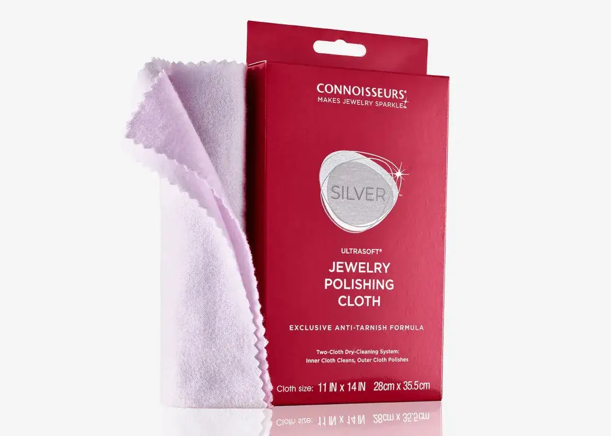 Jasnoróżowa ściereczka do polerowania srebra obok czerwonego opakowania z napisem "JEWELRY POLISHING CLOTH".