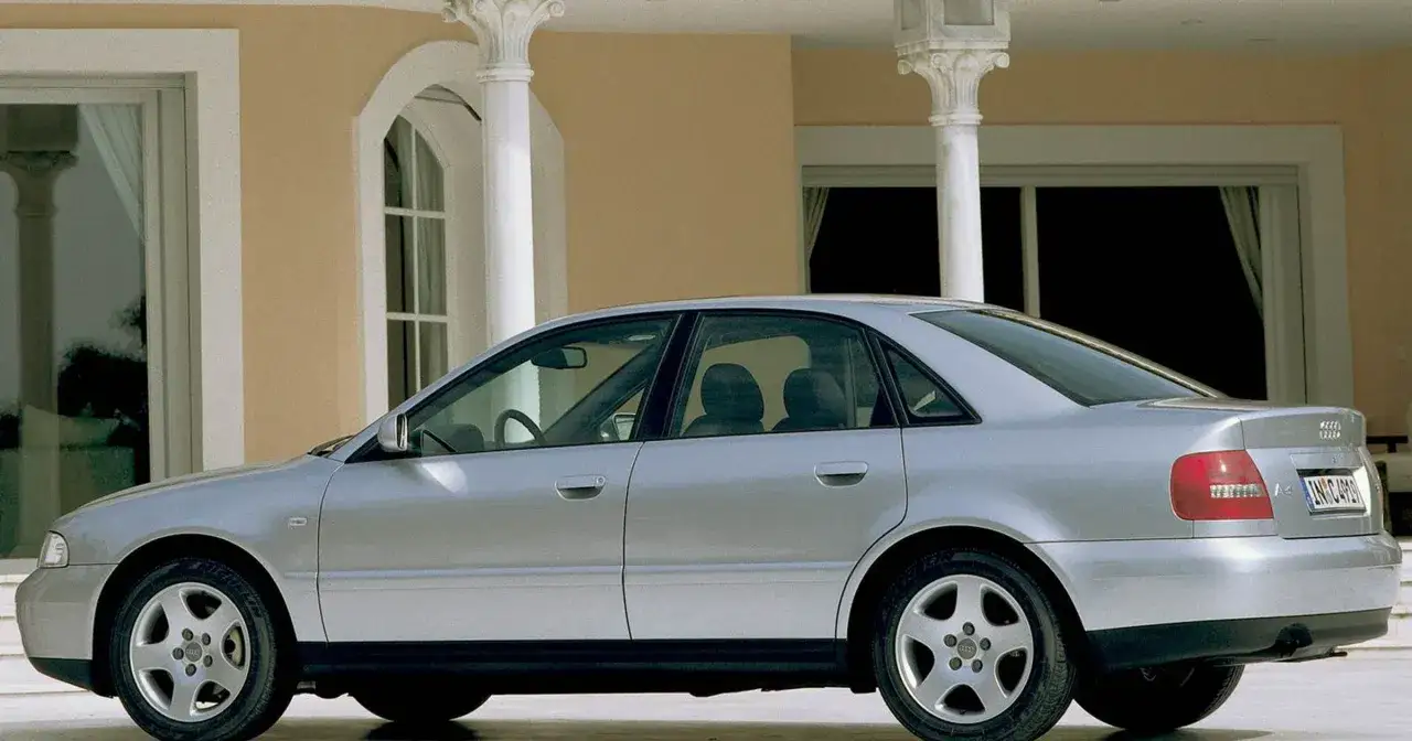 Srebrne Audi A4 B5, sedan, stoi przed budynkiem z kolumnami.