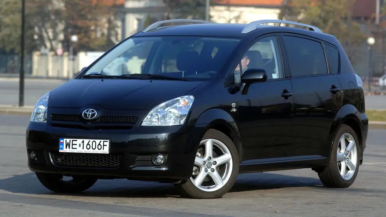 Czarna Toyota Corolla Verso z relingami dachowymi, zaparkowana na ulicy.