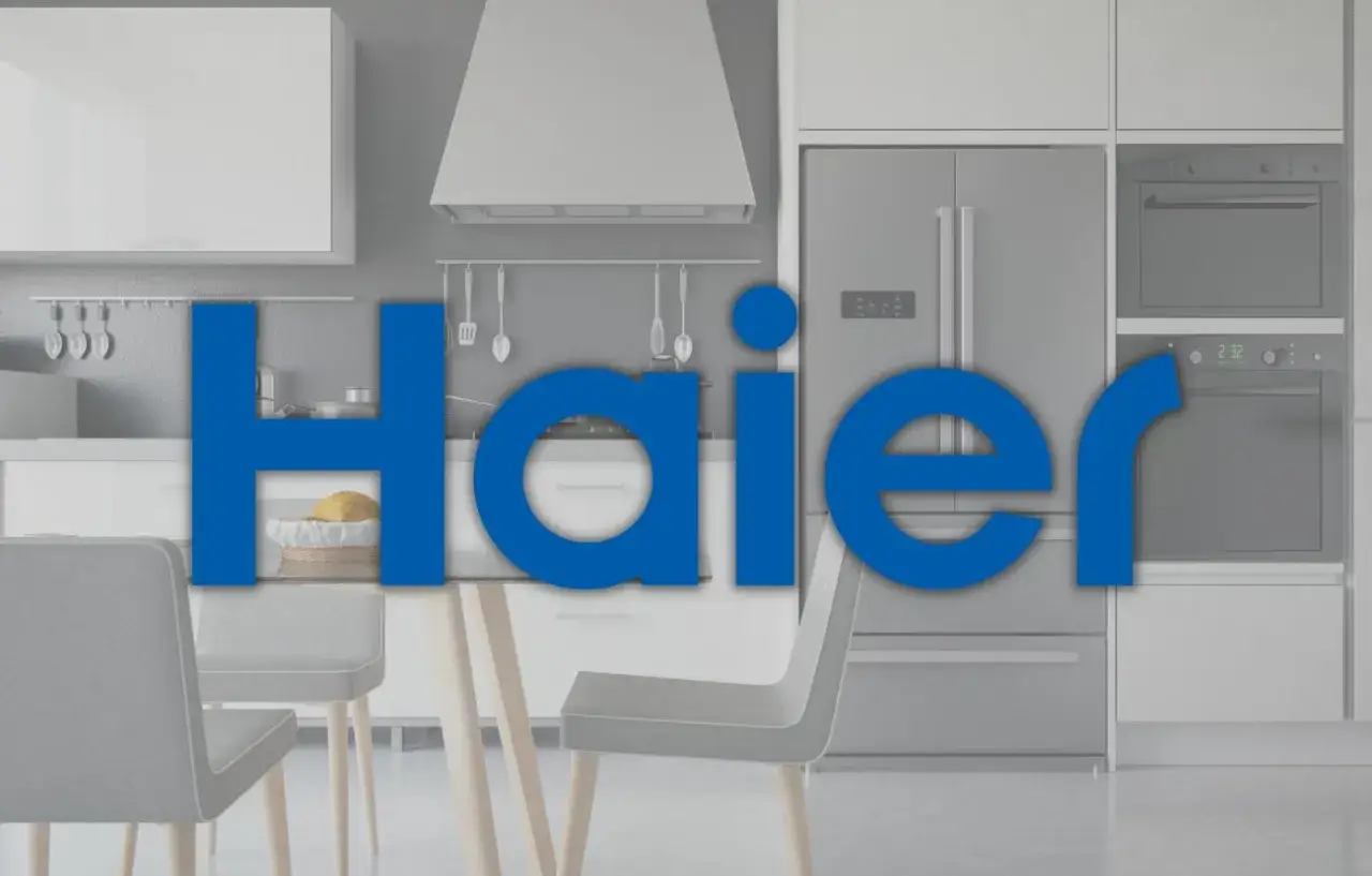 Nowoczesna kuchnia z lodówką i piekarnikiem. Duży napis "Haier" informuje, haier co to za firma, znana z produkcji sprzętu AGD.