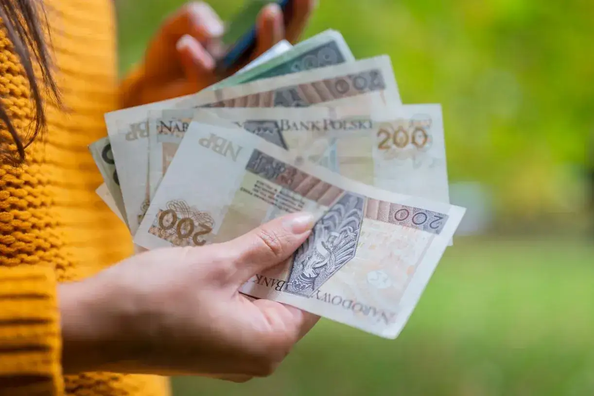 Dłoń trzyma polskie banknoty 200 zł. To może być dodatek wyrównawczy, który pomoże w codziennych wydatkach.