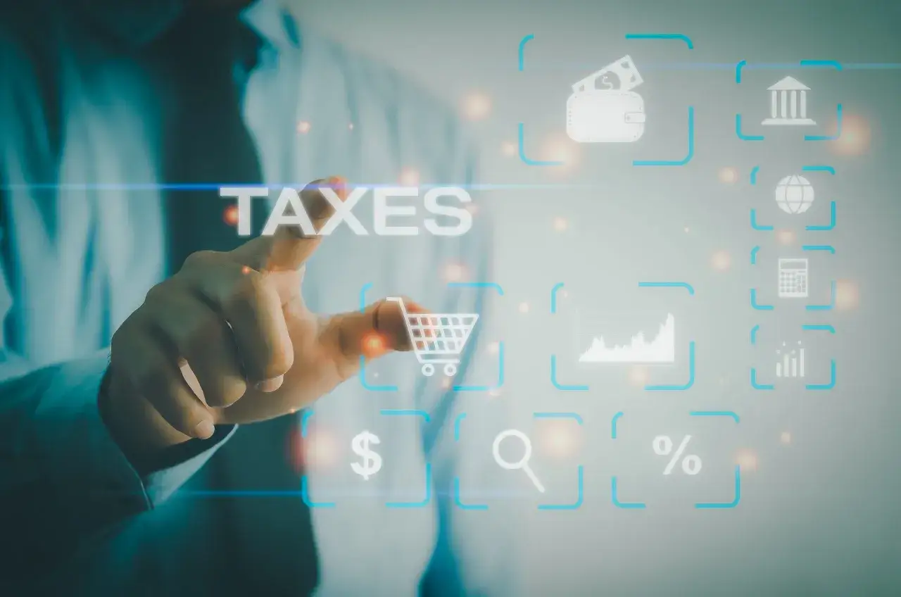 Dłoń dotyka ekranu z napisem TAXES. Wokół ikony symbolizujące finanse, handel i analizę danych, jak koszyk, portfel, wykresy, lupa, procent, kalkulator, bank i globus. To cyfrowy świat zarządzania podatkami, gdzie każdy element ma swoje znaczenie w sys...