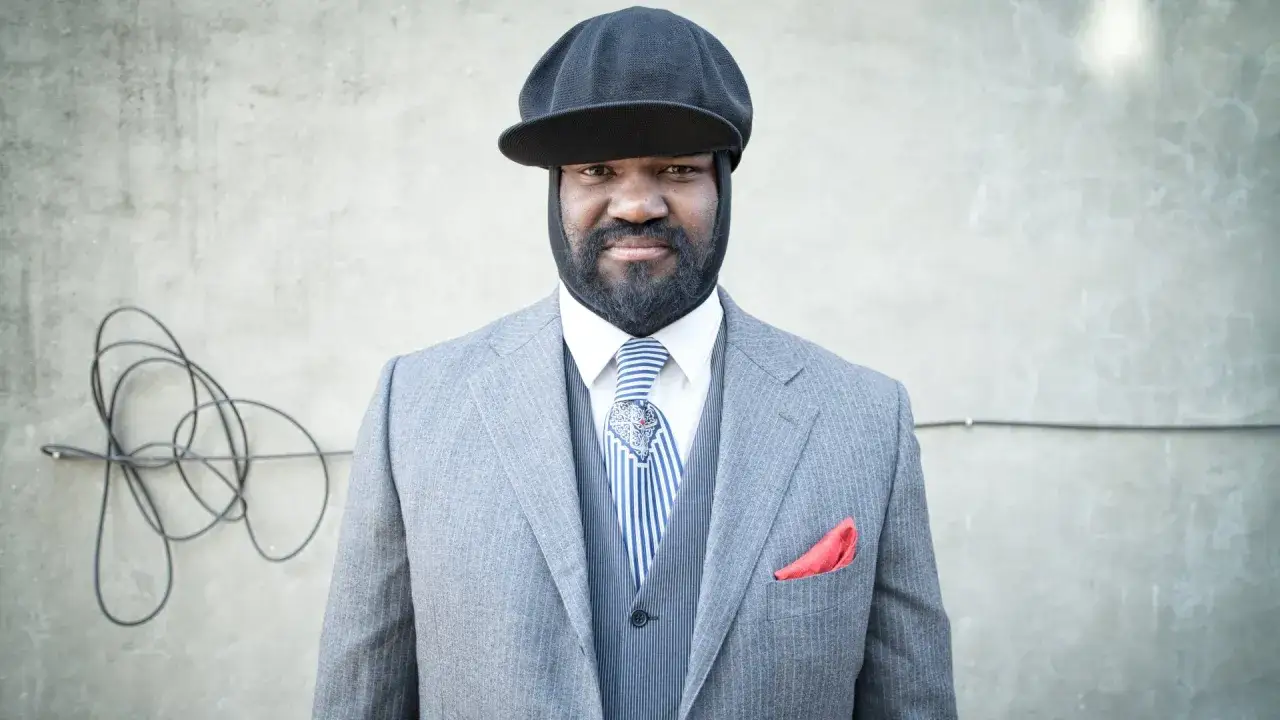 Gregory Porter w eleganckim garniturze i czapce, gotowy na koncert.
