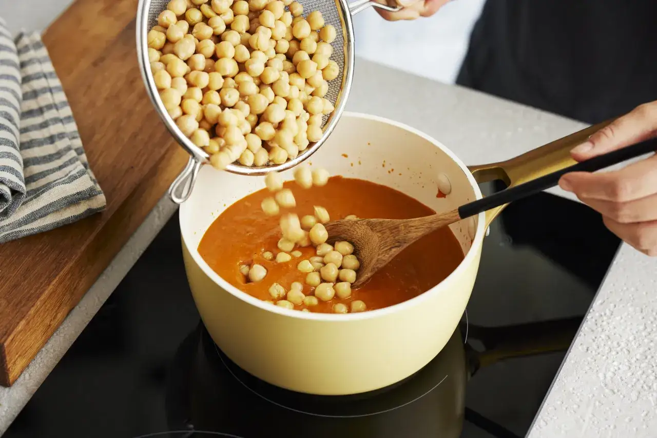 Kichererbsen werden in einen Topf mit Curry gegeben. Perfekt für die Zubereitung von Kichererbsen-Curry zum Einfrieren.